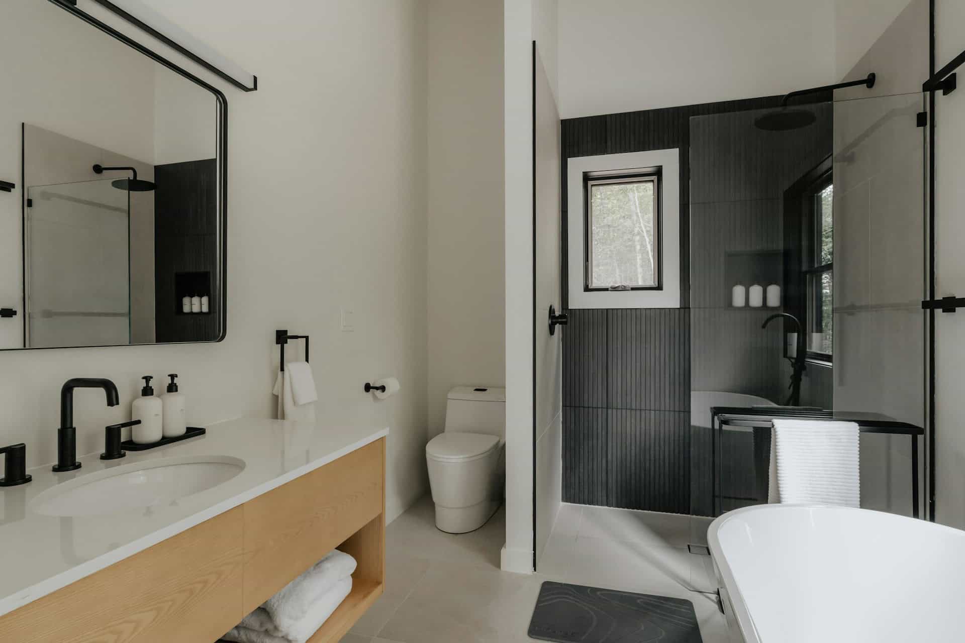Modern bathroom with white vanity, black fixtures, walk-in glass shower, and freestanding bathtub